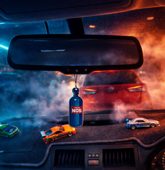 Car interior with a NOS bottle hanging from the rearview mirror, surrounded by toy cars.