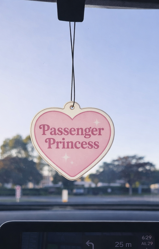 Heart-shaped 'Passenger Princess' air freshener hanging from a car's rearview mirror.
