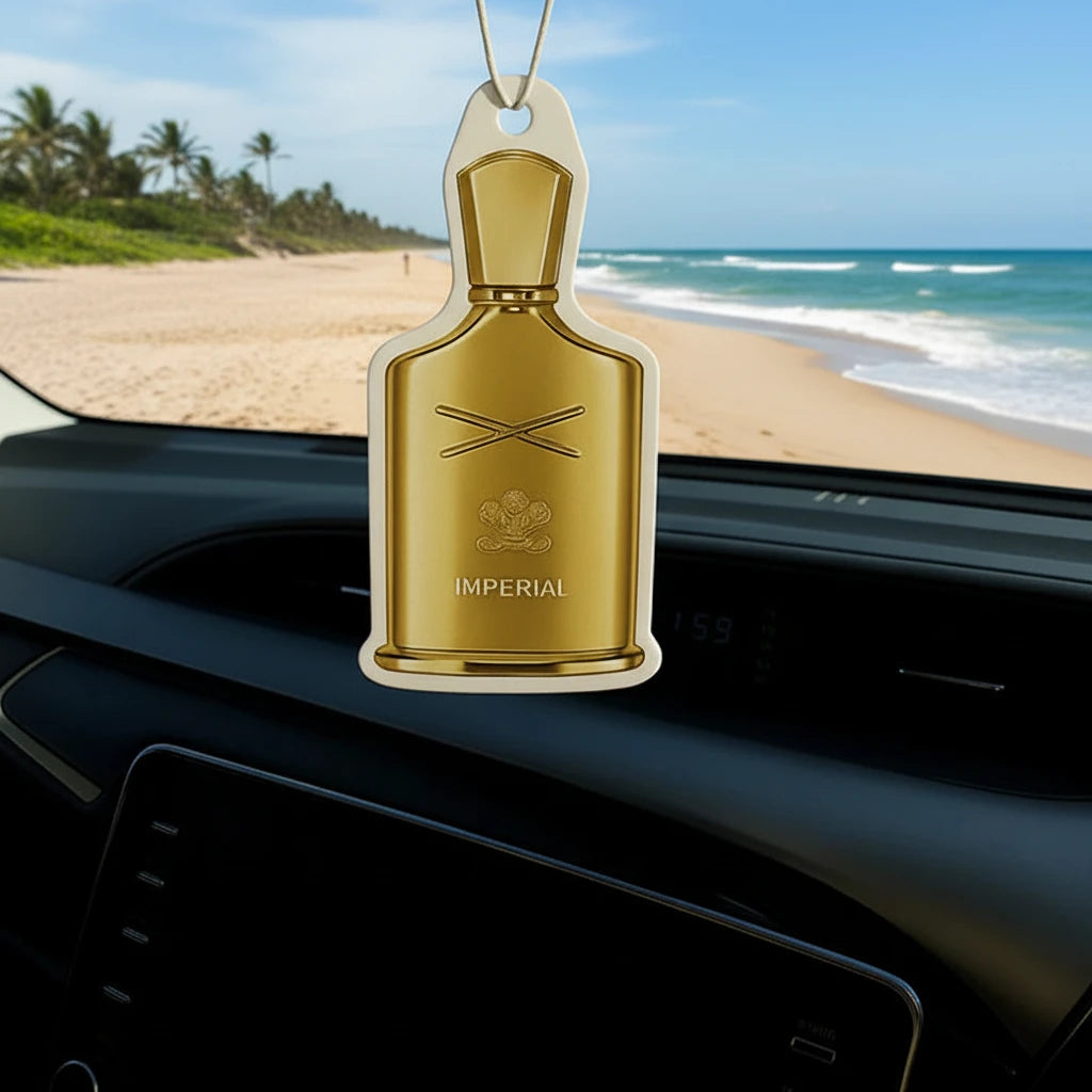 Gold car air freshener shaped like a bottle with 'Imperial' branding hanging from a car's rearview mirror.