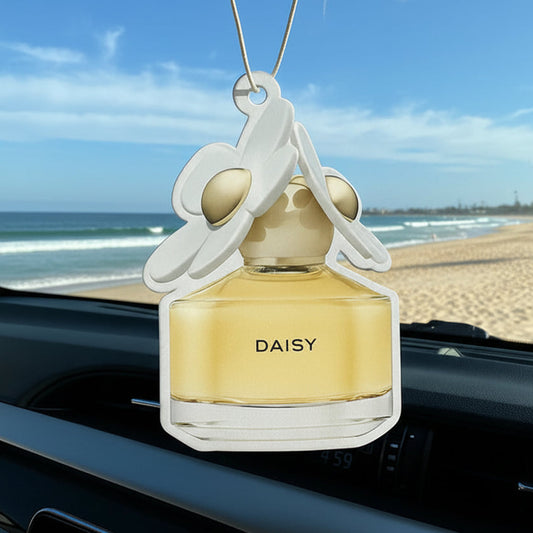Car air freshener shaped like a perfume bottle with 'DAISY' branding hanging from a car's interior.